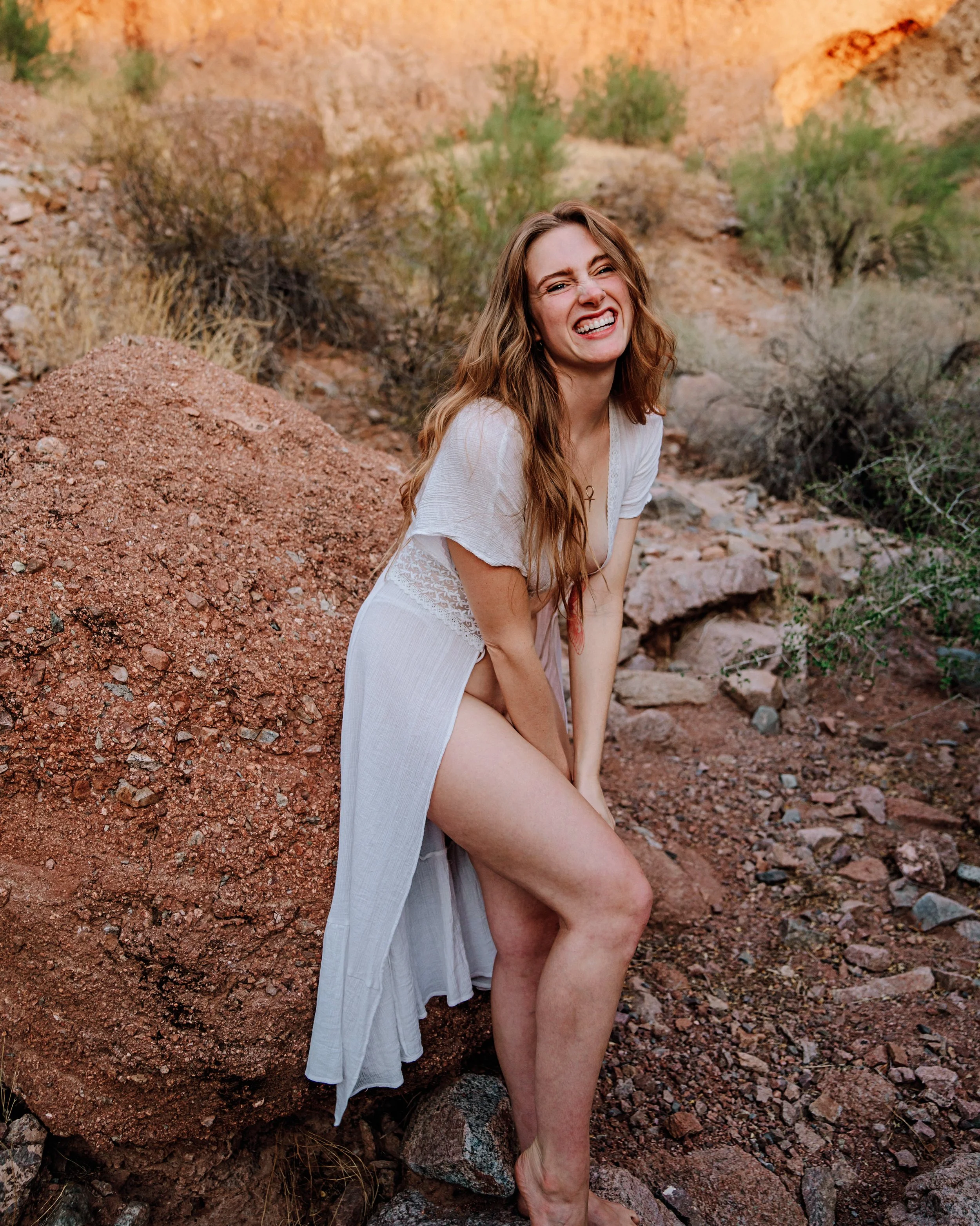 Madi smiling in the desert, wearing a white dress